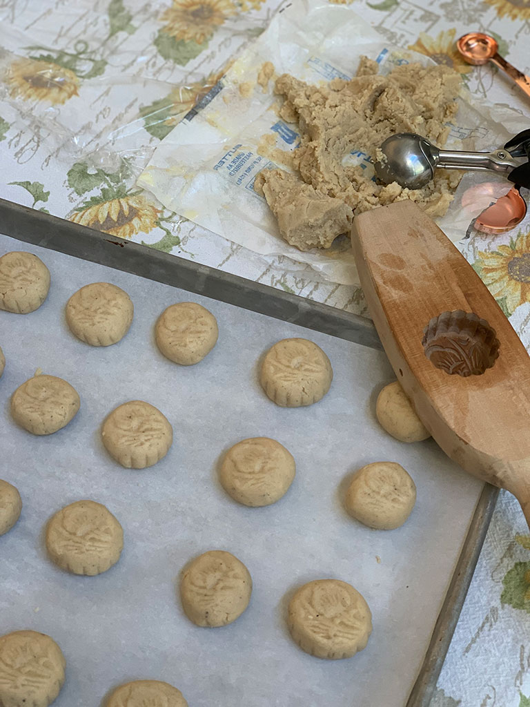 Raw cookies on cookie sheet with dough and cookie mould in background